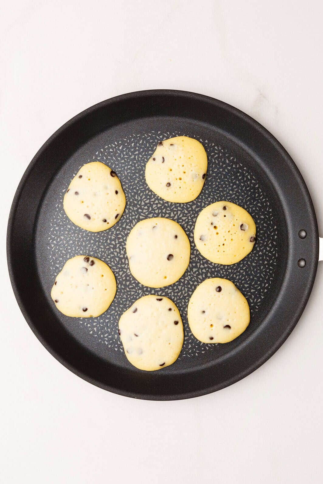 Top image of a skillet with seven mini chocolate chip pancakes.