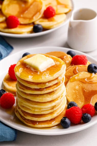 A stack of silver dollar pancakes topped with butter and syrup.