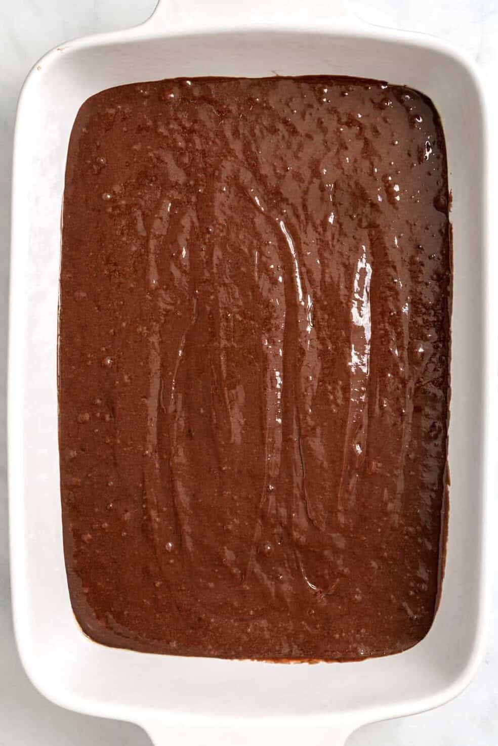 Top down image of a 9 x 13 casserole baking dish with chocolate cake batter.