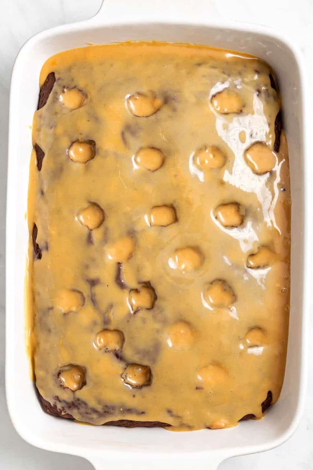 Top image of a 9 x 13 casserole baking dish with chocolate poke cake with caramel on top.