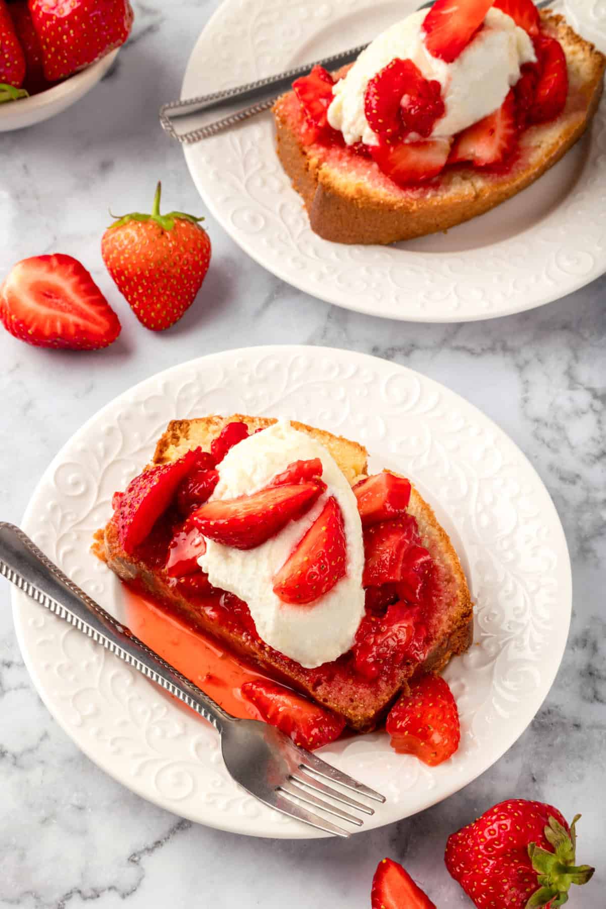 Slice of strawberry shortcake poundcake served on a decorative white round plate.