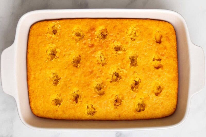 Overhead image of holes poked into a yellow cake.