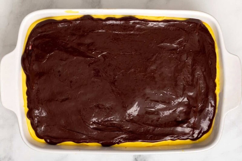 Chocolate glaze poured over Boston cream poke cake.
