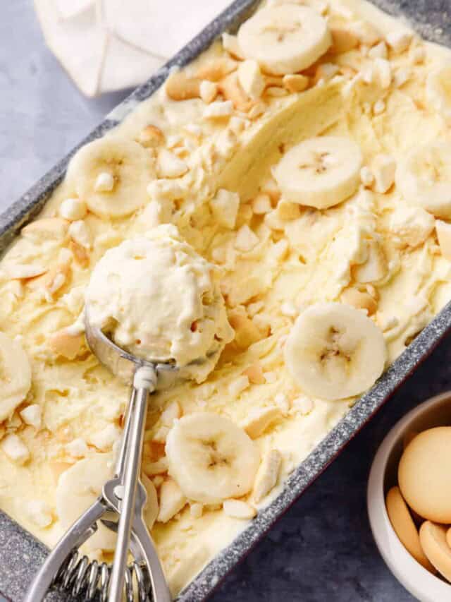 banana ice cream An ice cream scoop holding a scoop of banana pudding ice cream on top of a loaf pan.