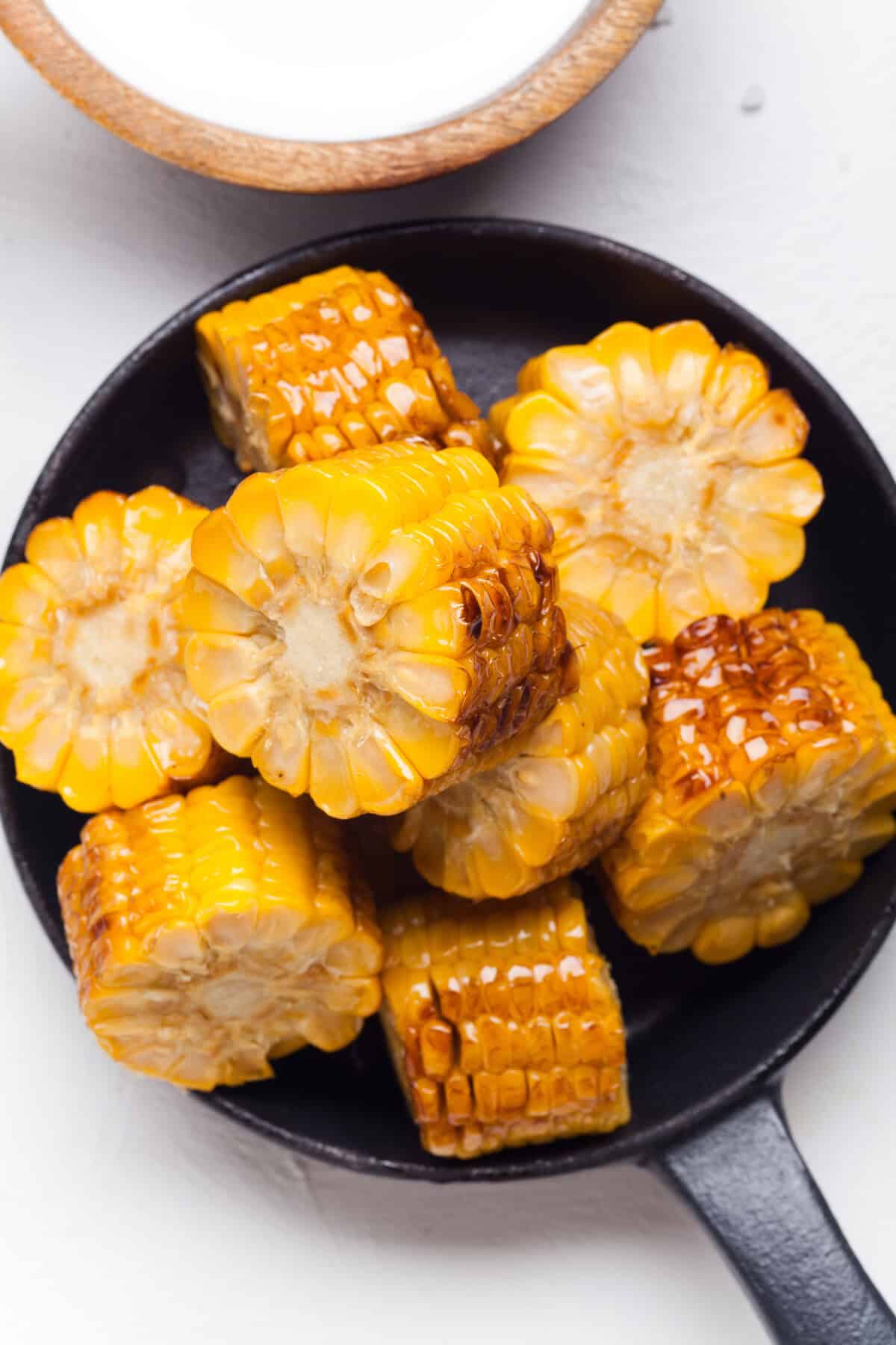 Grilled corn on the cob in a pan, cut into smaller pieces.