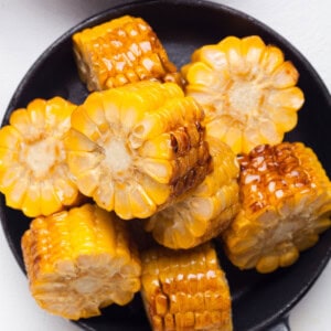 Grilled corn on the cob in a pan, cut into smaller pieces.