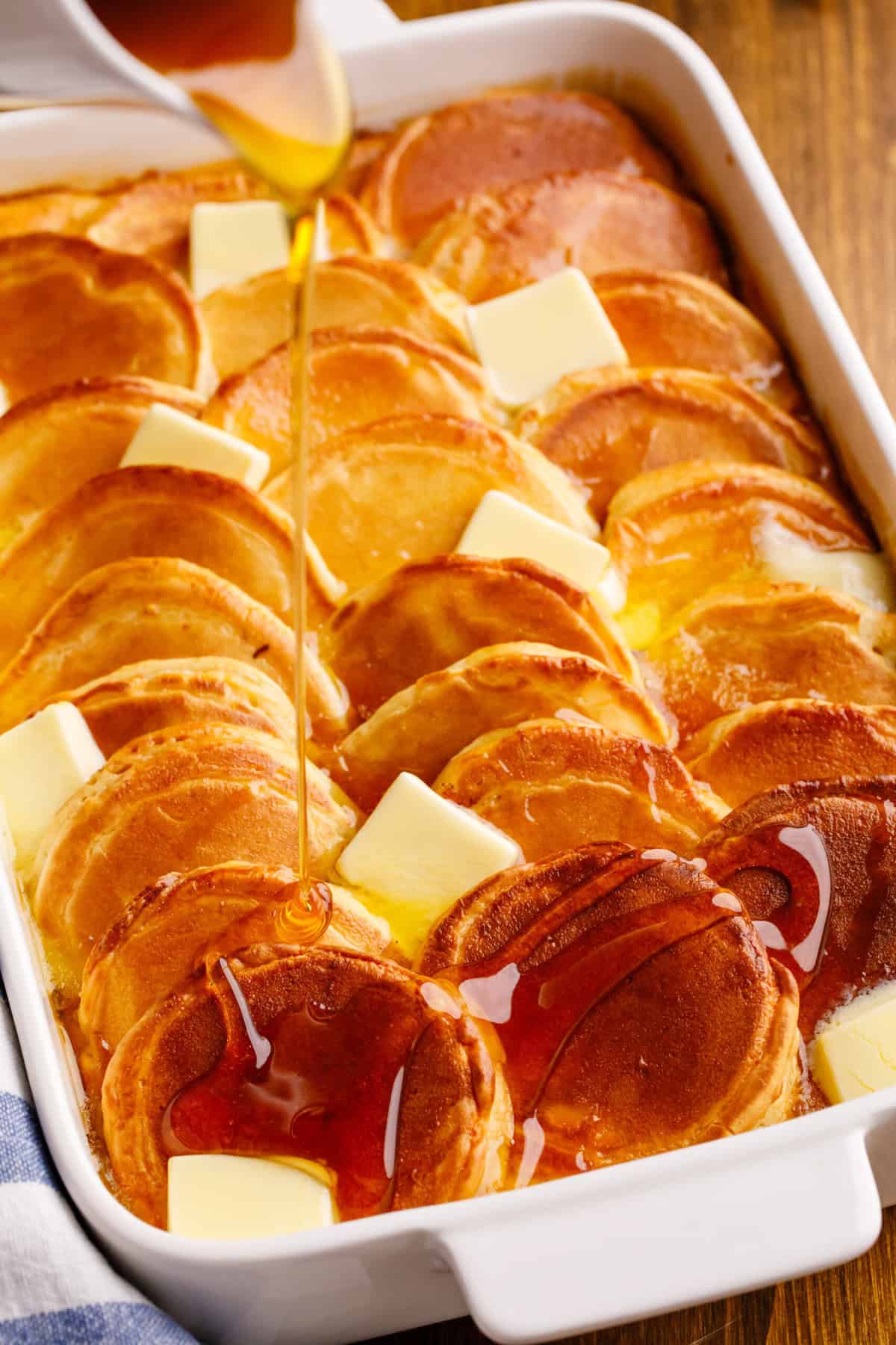 Maple syrup pouring over overnight pancake casserole.