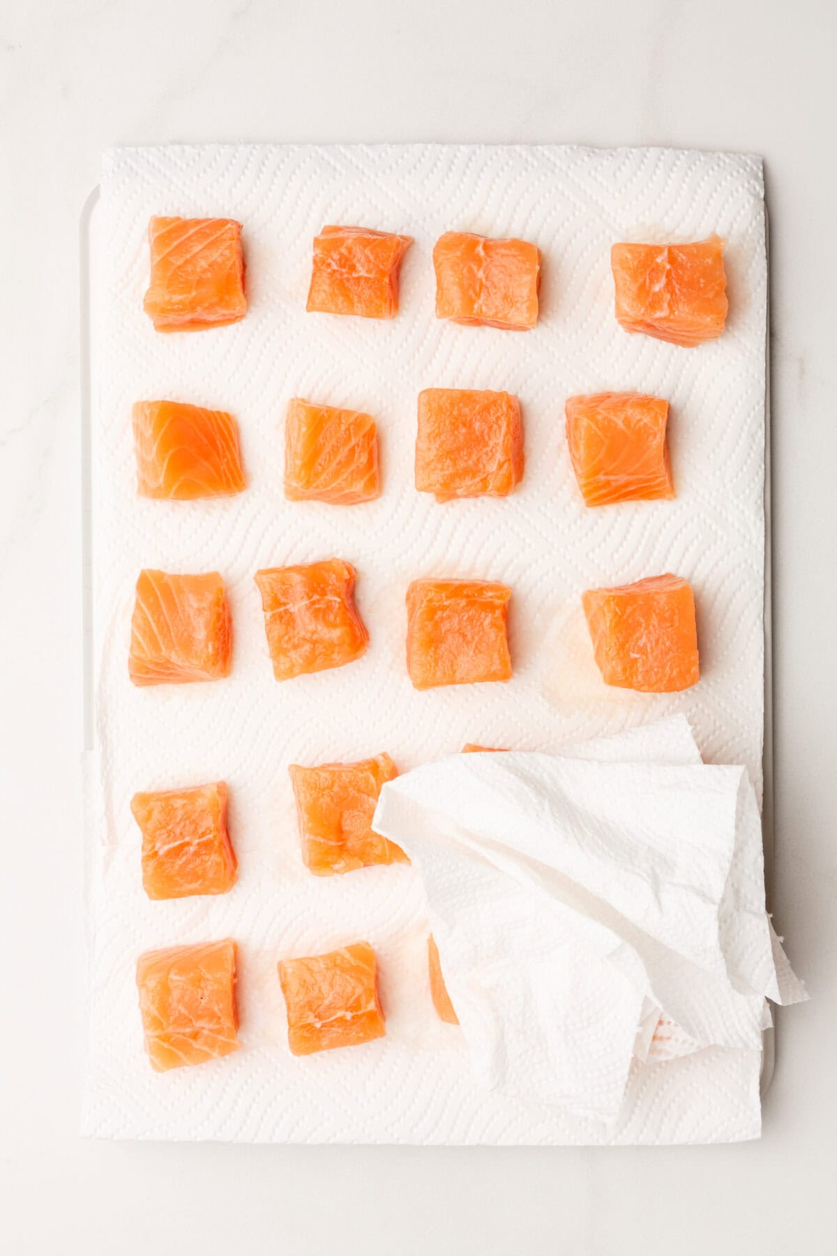 Overhead view of salmon bites being dried with paper towel