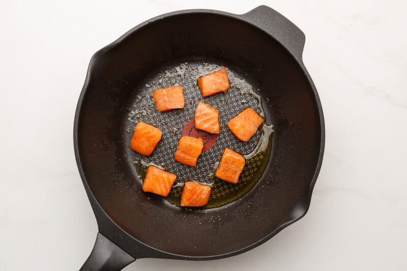 Salmon cubes cooking in a skillet.