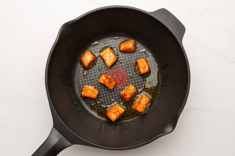 Crispy salmon cubes in a cast iron skillet.