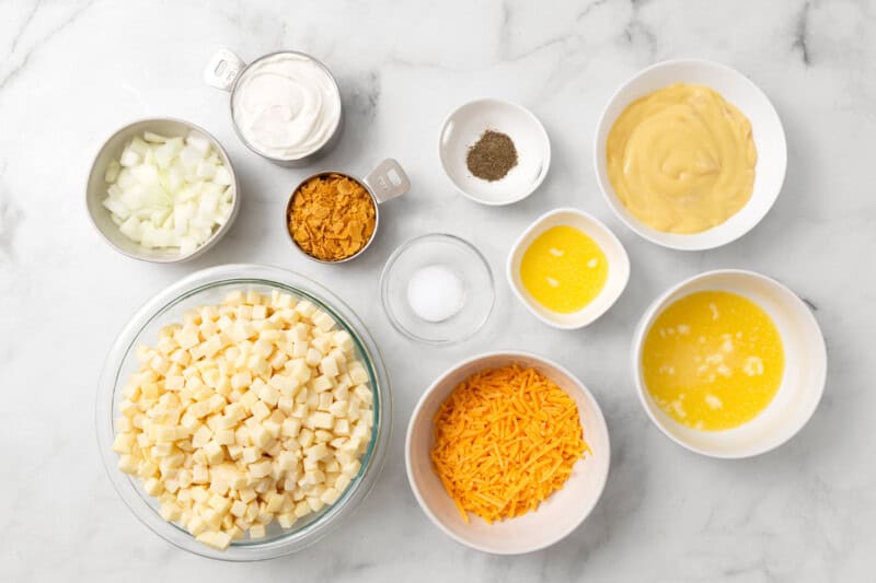 Ingredients for Amish funeral potatoes in separate bowls on a marble countertop.