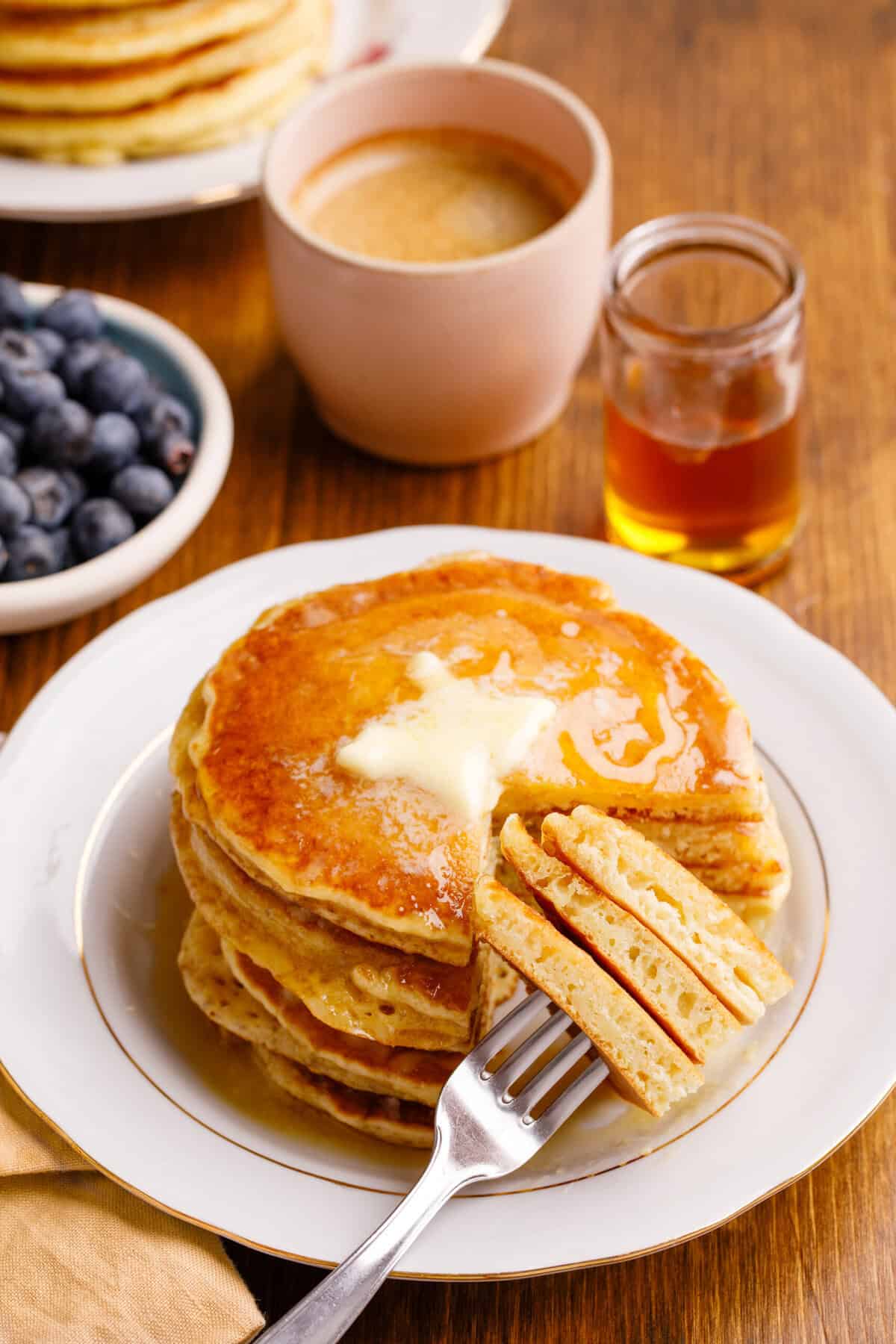 Stack of pancakes with syrup with a slice on a fork.