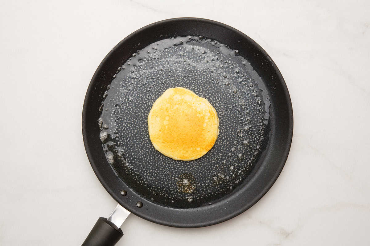 Cracker barrel pancake cooking in a skillet.