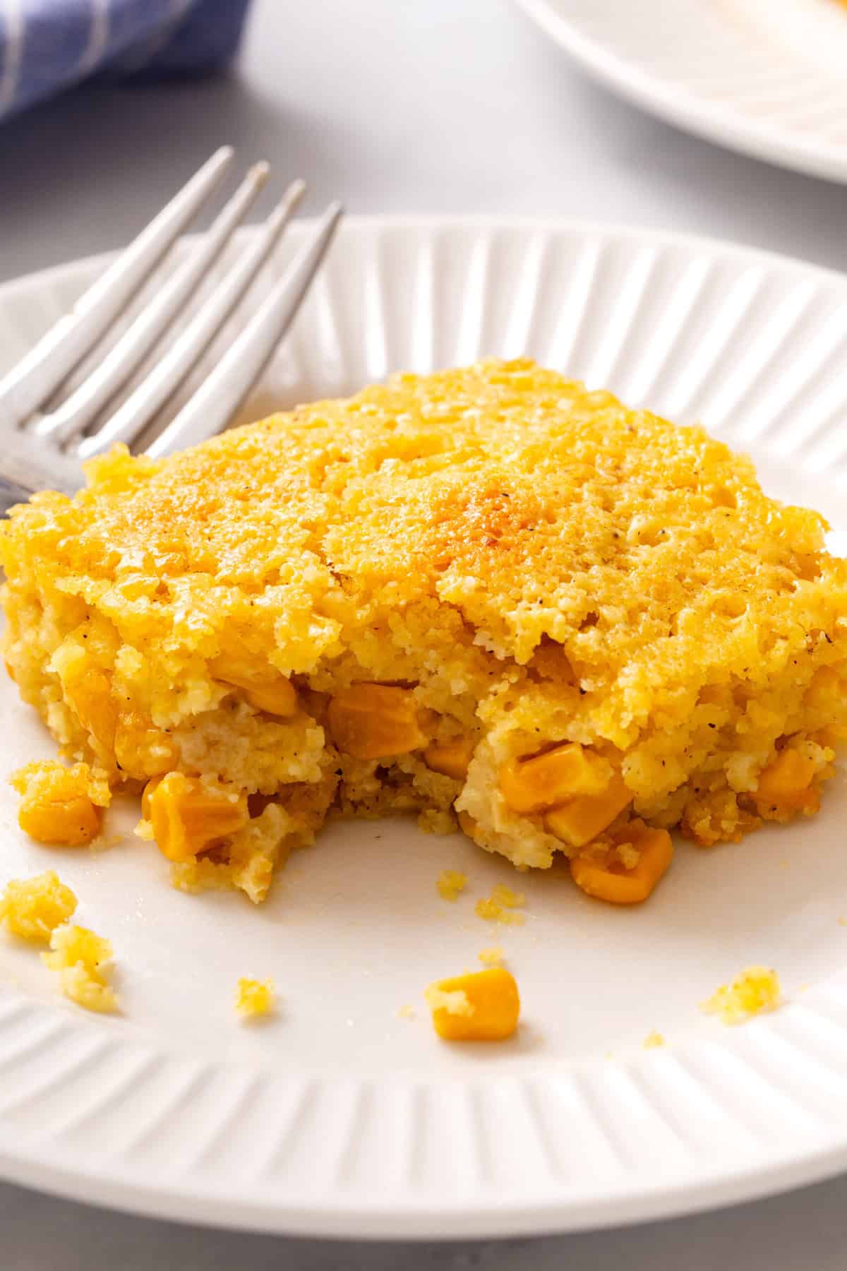 Slice of corn souffle on a white plate.