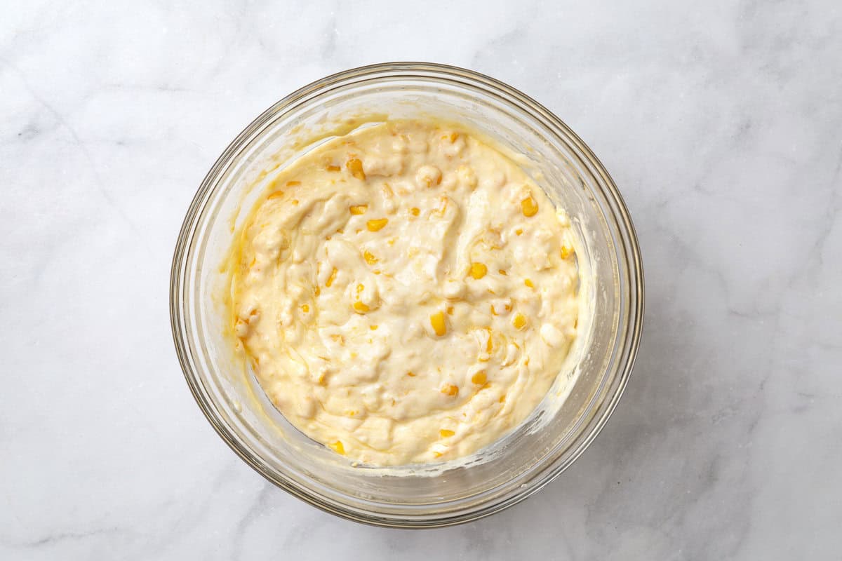 wet ingredients for corn souffle mixed together in a glass bowl.
