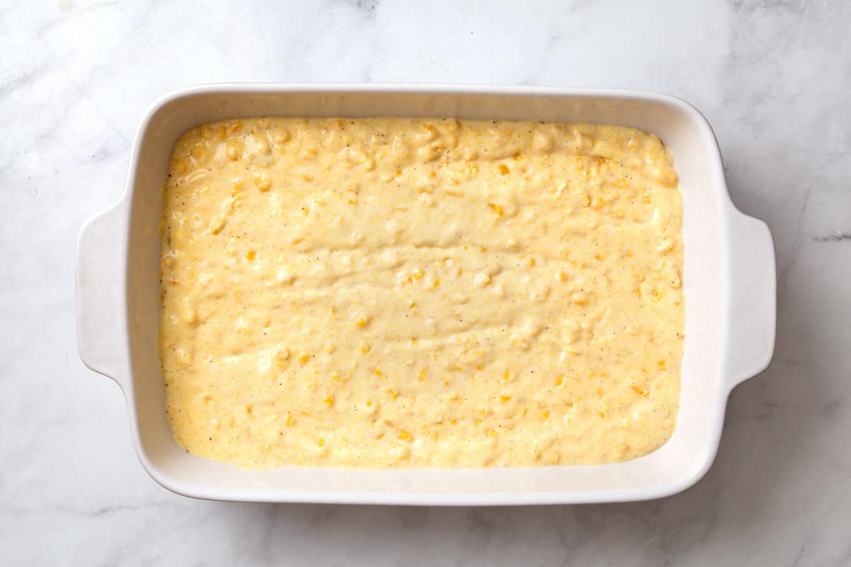 unbaked corn souffle in a white casserole dish. 