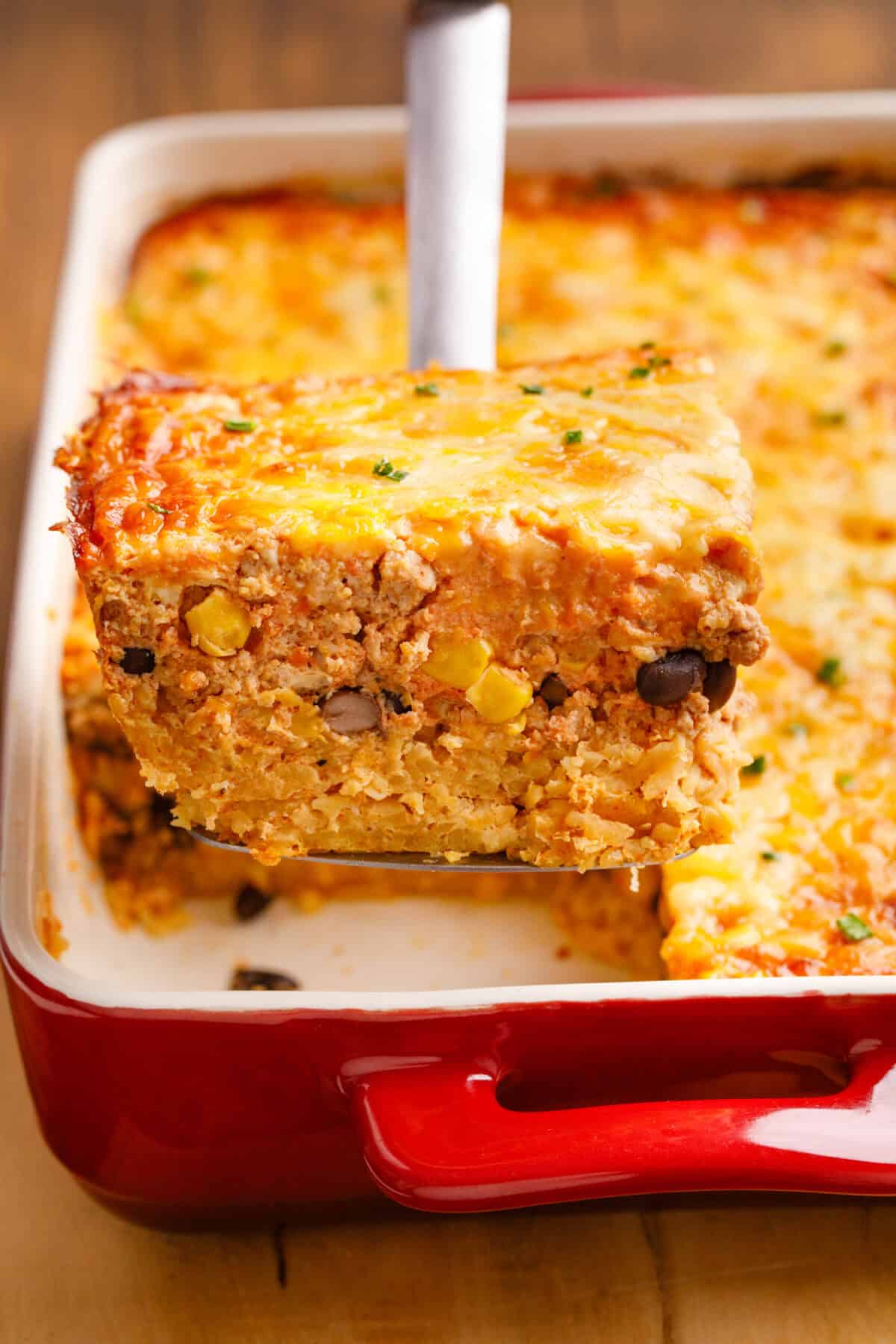 Mexican Breakfast Casserole on a serving spoon coming out of a baking dish.