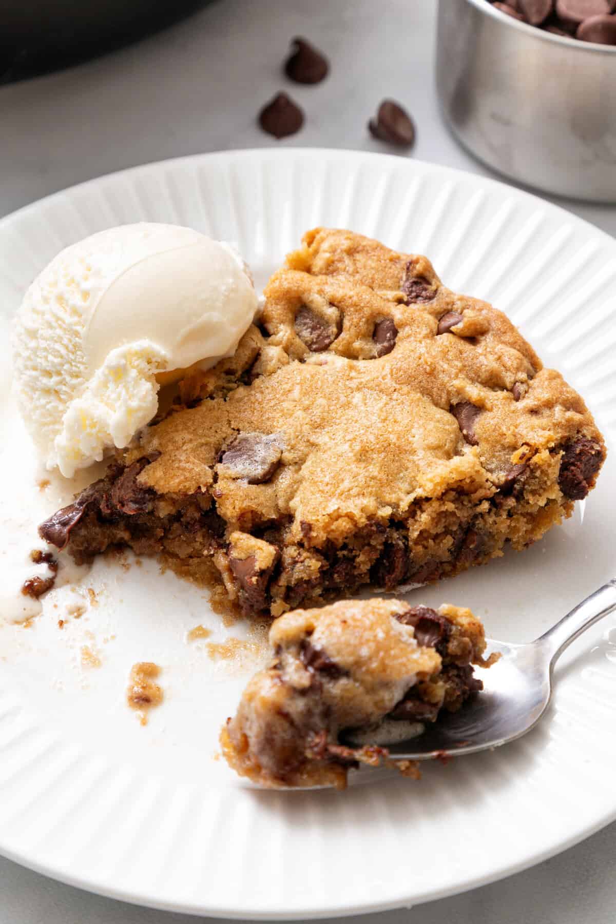 slice of a chocolate chip skillet cookie on a white plate with a vanilla ice cream