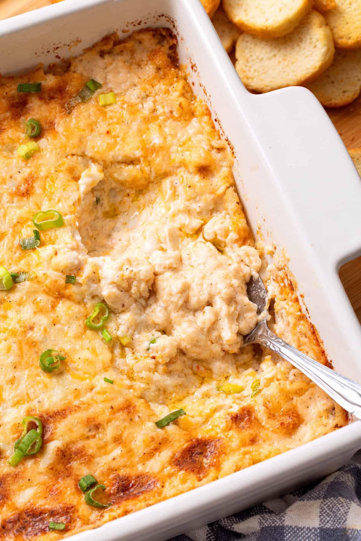 Hot crab dip in a baking dish with a spoon. 
