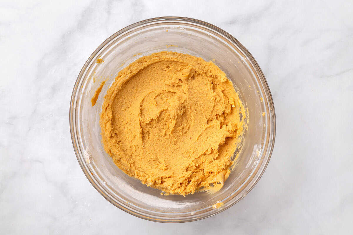 pumpkin cookie dough batter top down image of a large glass mixing bowl with pumpkin cookie batter.