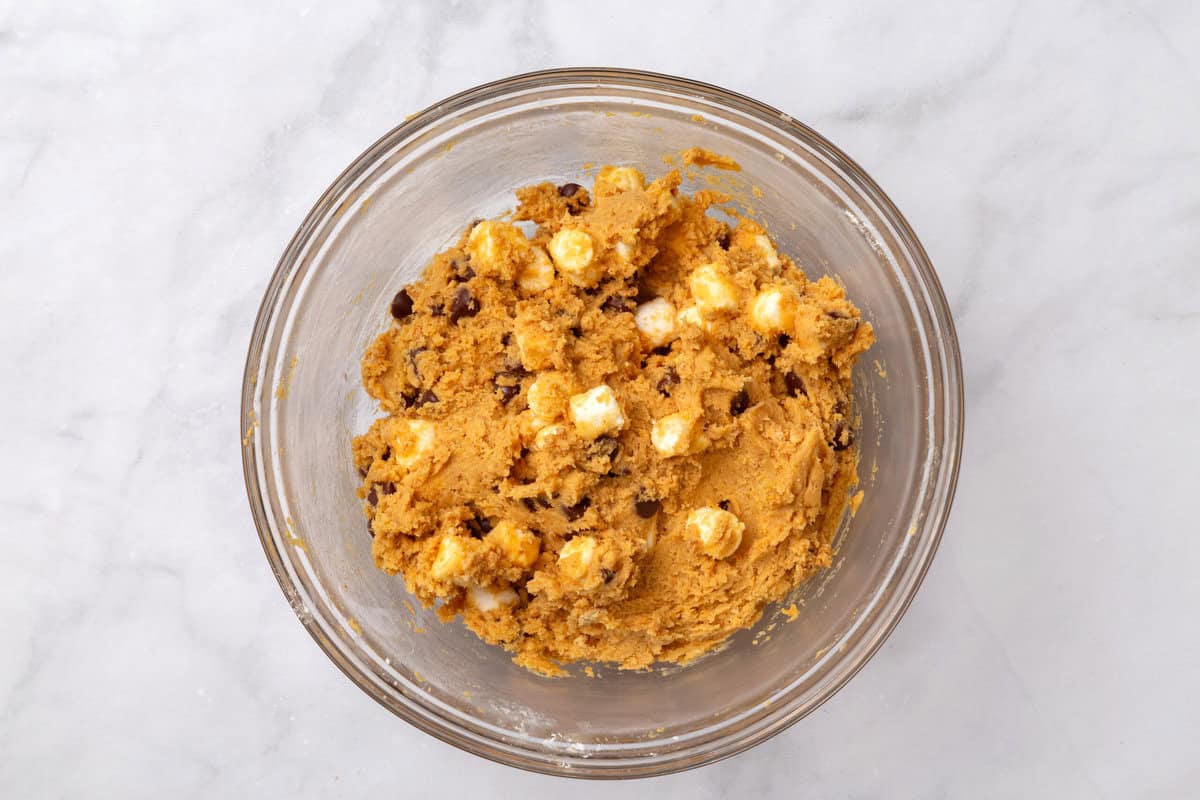 cookie dough batter with marshmallows and chocolate chips pumpkin s'more cookie batter in a large glass bowl.