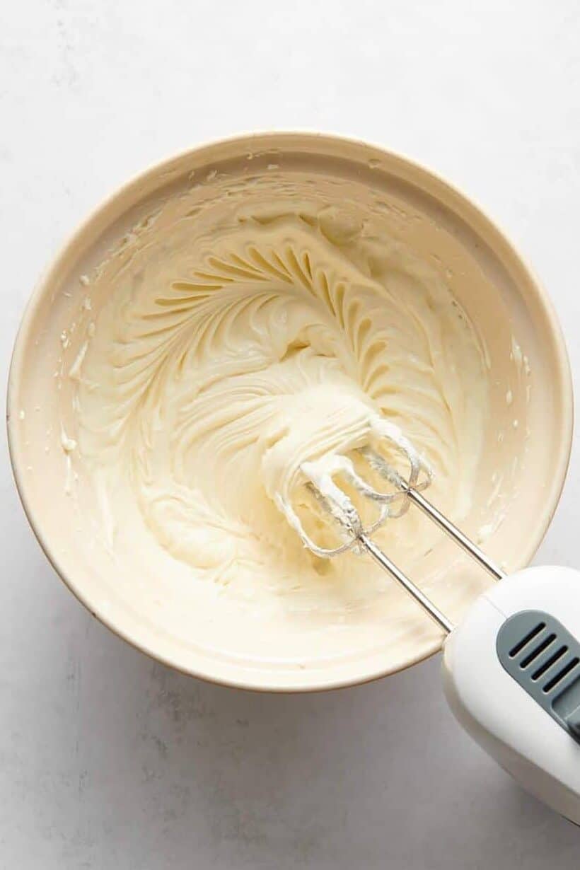 cheesecake filling batter in a large bowl with an electric mixer