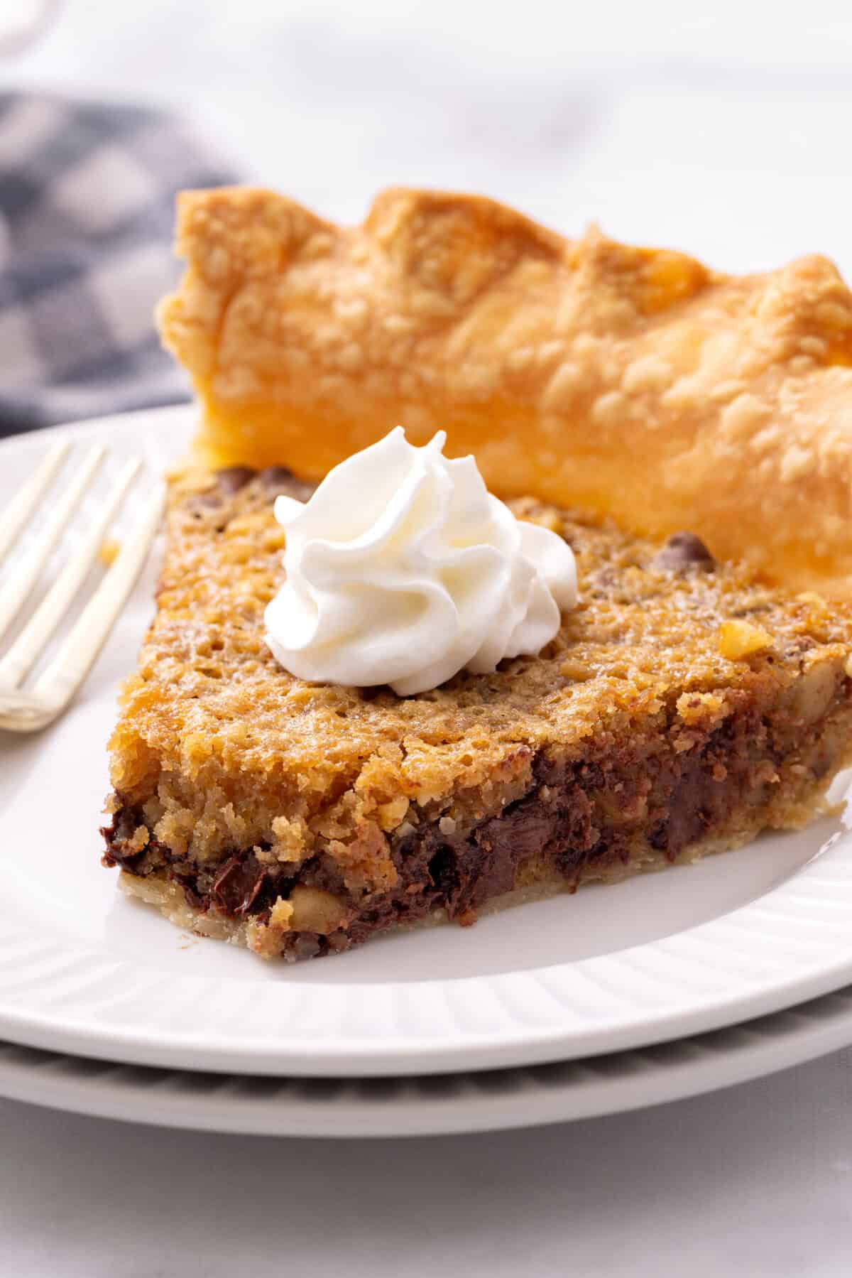 piece of derby pie with whipped cream on a plate.