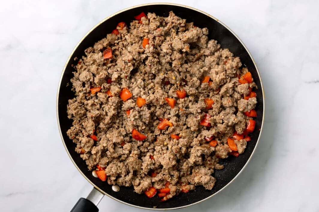 Sausage and peppers cooking in a skillet. 