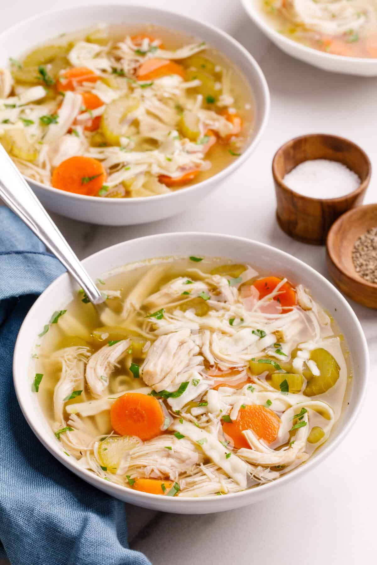A bowl of Crockpot Chicken Noodle Soup with a spoon sitting it in. 