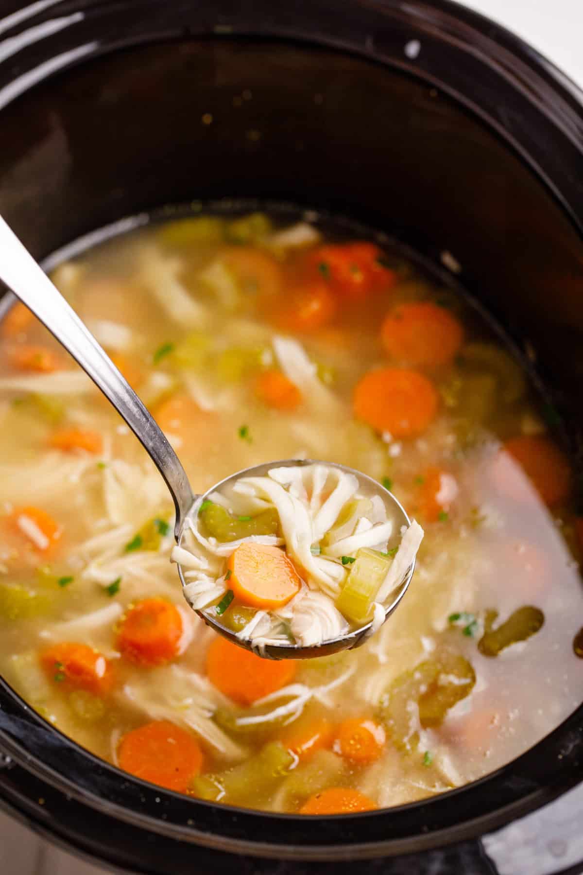 A ladle scooping out a serving of Crockpot Chicken Noodle Soup. 