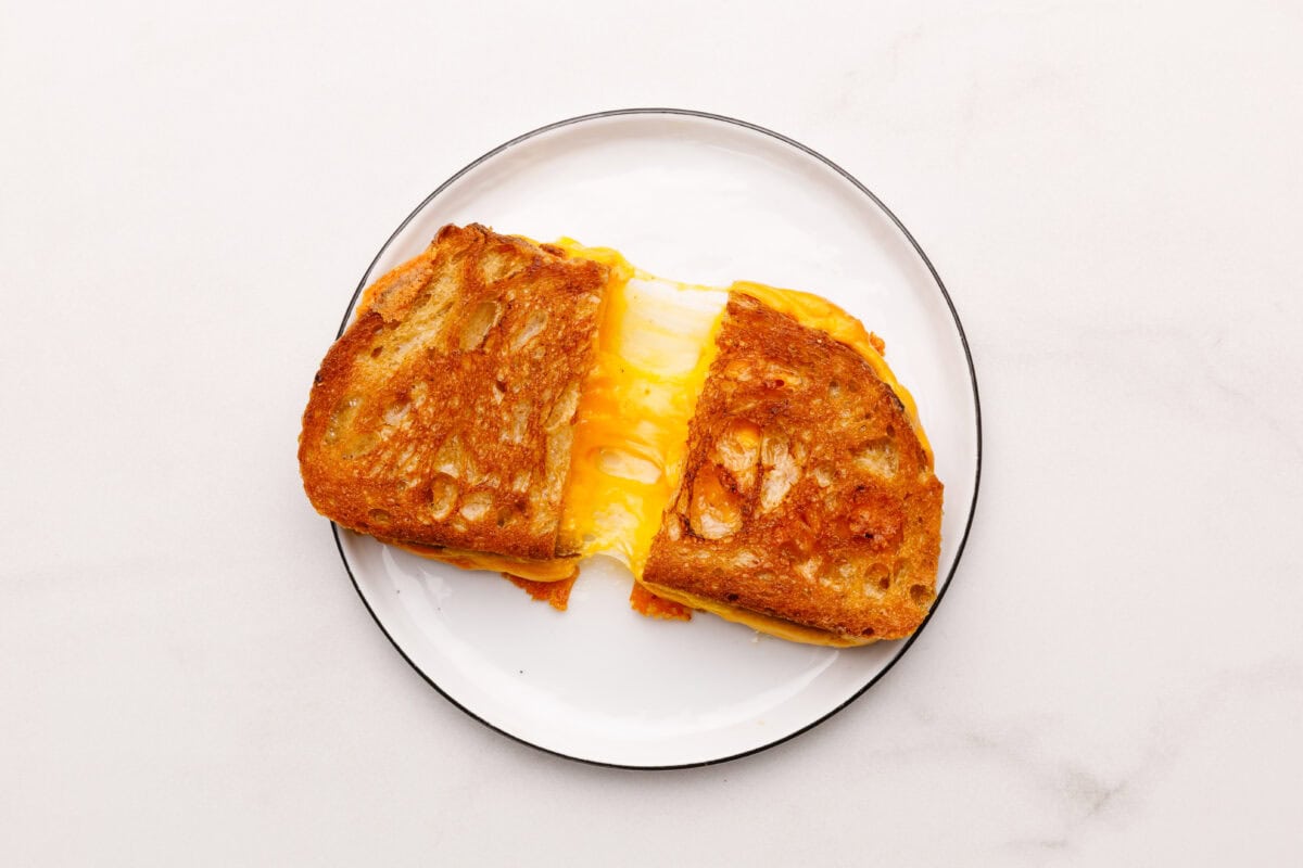 Grilled cheese sandwich on plate sliced in half.