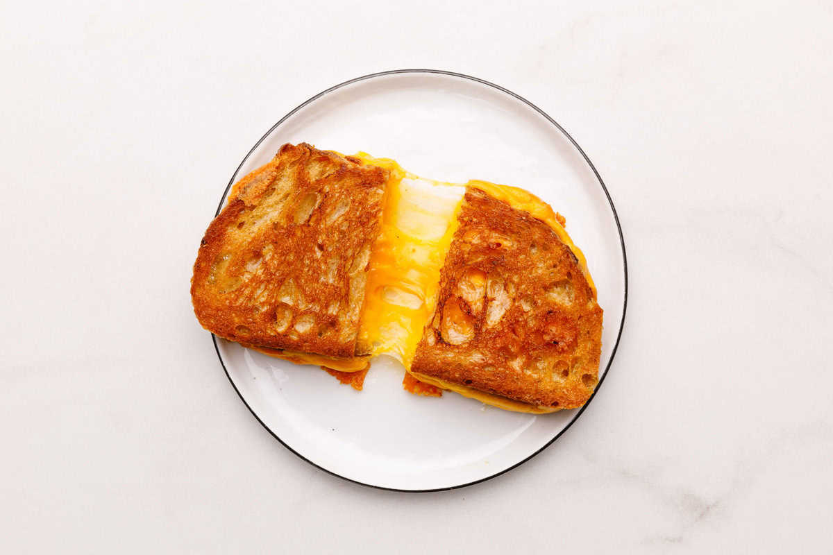 A sliced Grilled Cheese Sandwich sitting on a white plate. 