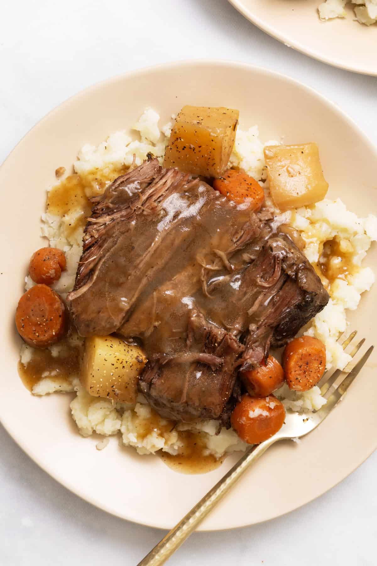 pot roast on a round plate with brown gravy.