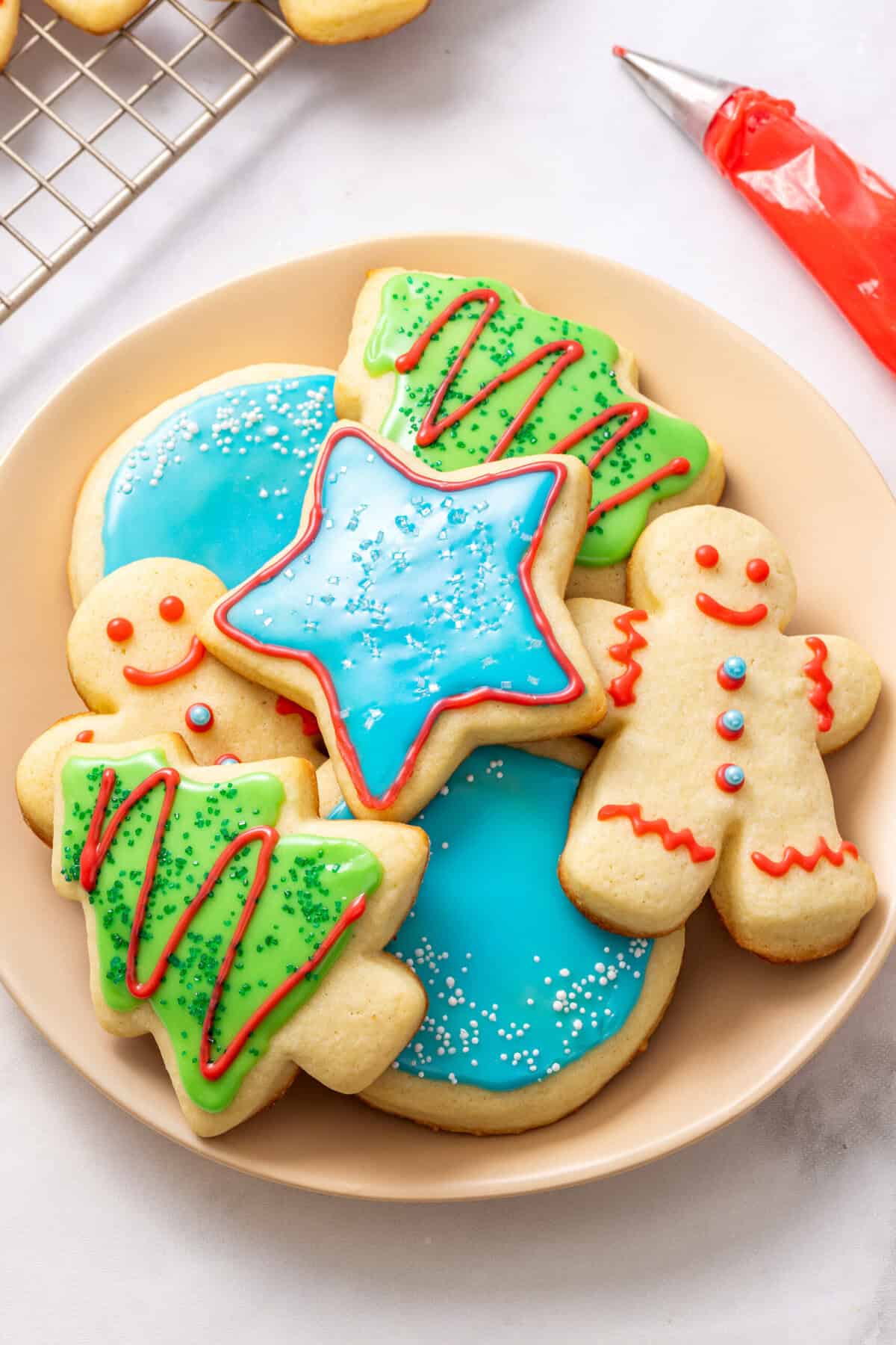 A plate of cut out sugar cookies decorated with sugar cookie icing. 