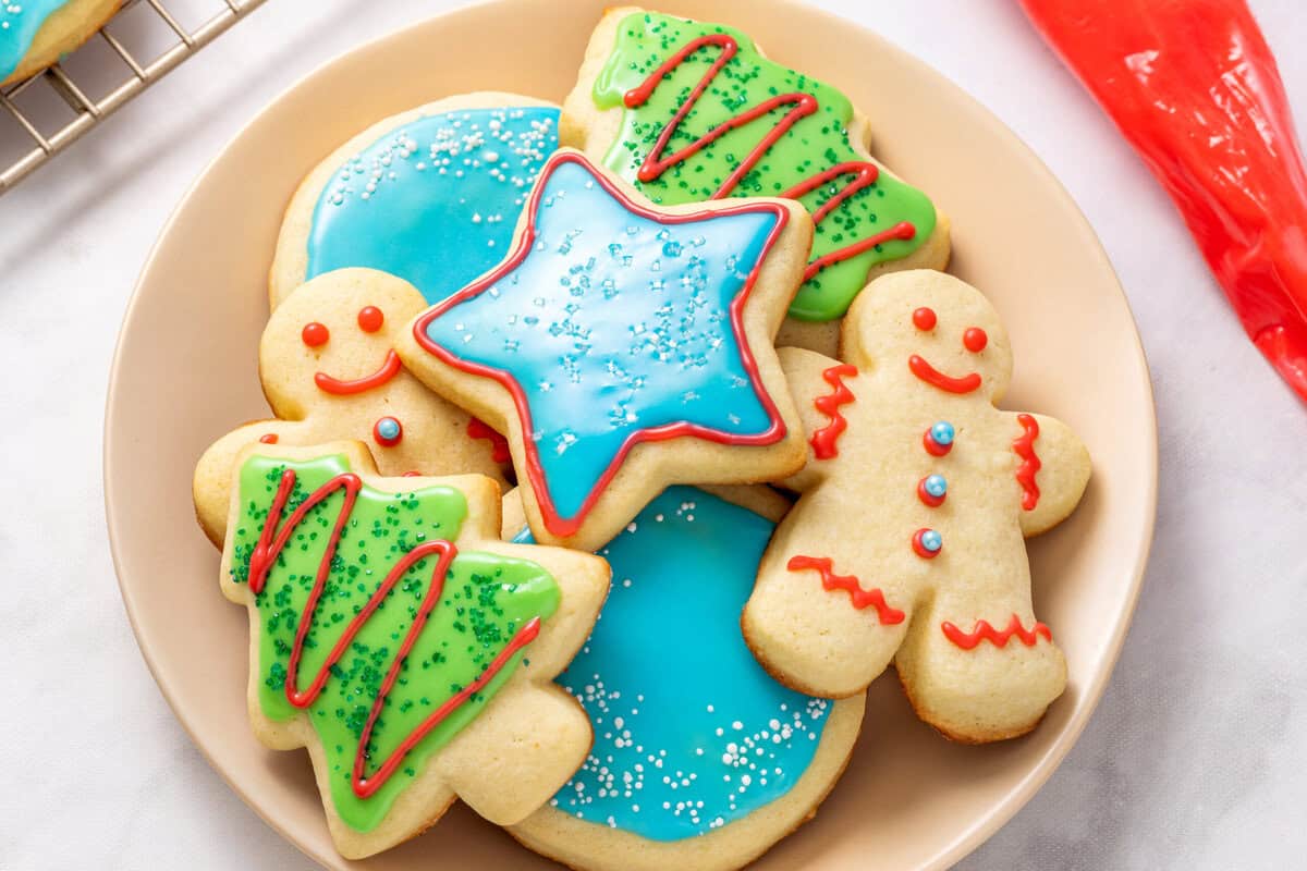 A plate of cutout sugar cookies decorated with sugar cookie icing. 