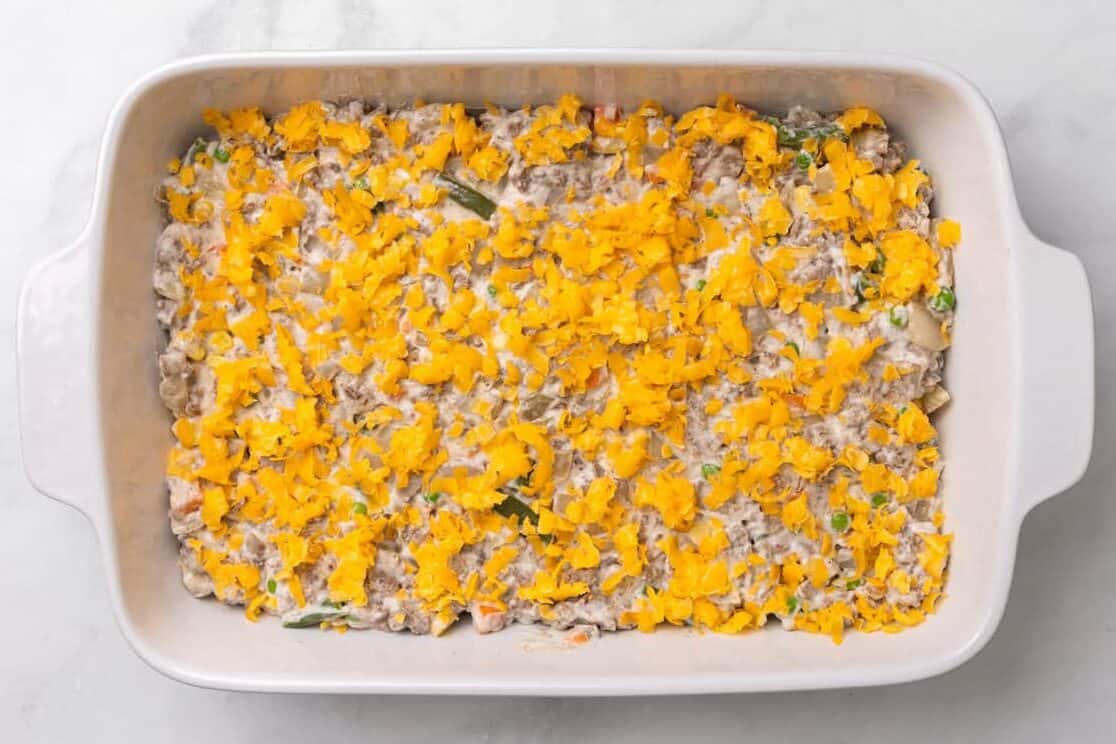 The mixture for Tater Tot Casserole with cheese on top. 