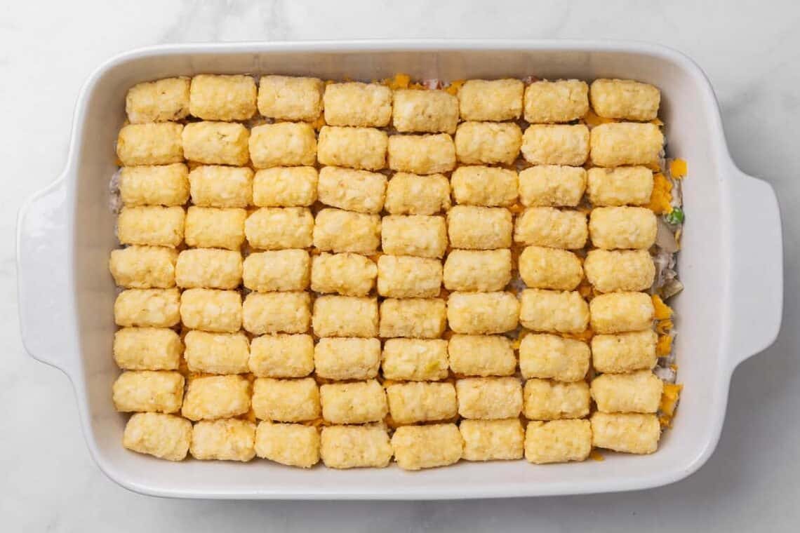 Placing the tater tots over the Tater Tot Casserole. 