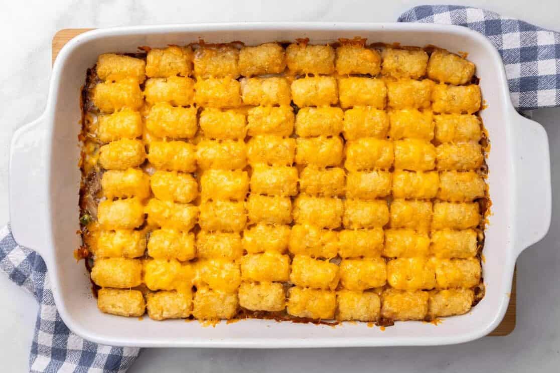A finished tater tot casserole sitting on a plaid tea towel. 