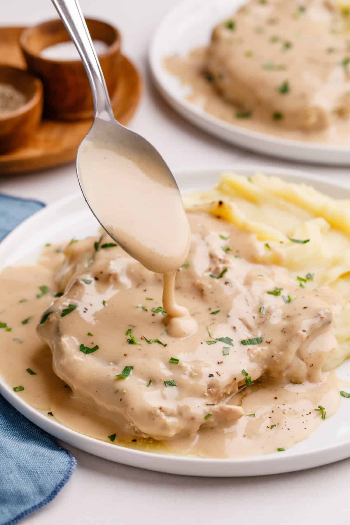 Gravy poured on pork chops gravy being poured over slow cooker pork chops.