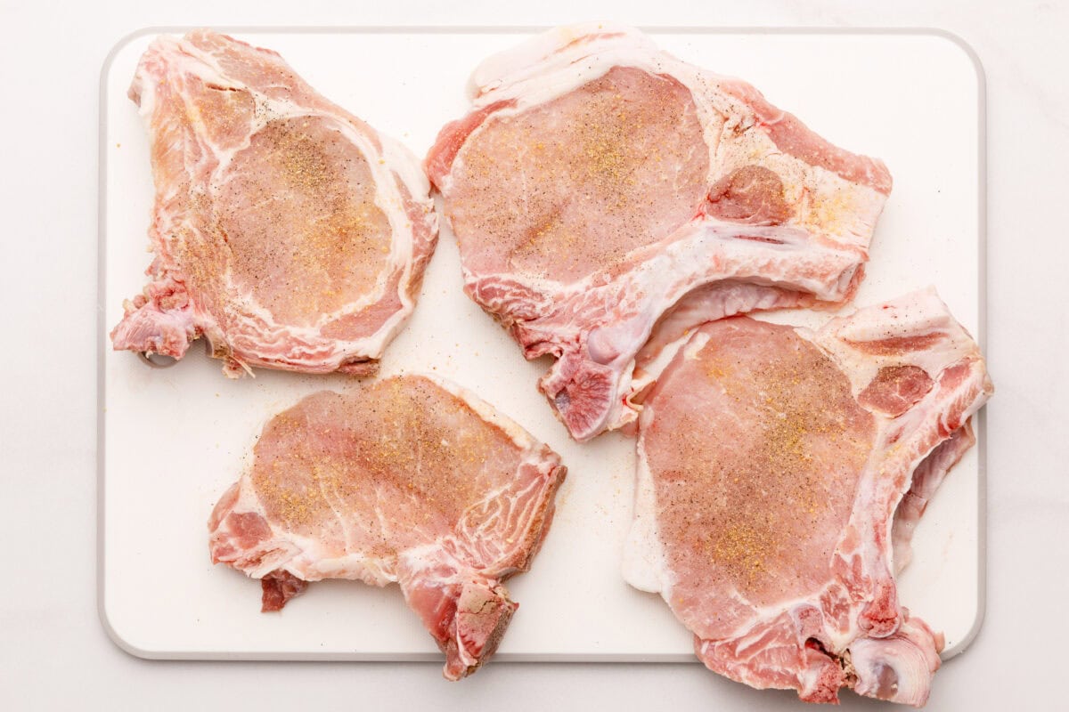 Seasoned pork chops on cutting board.