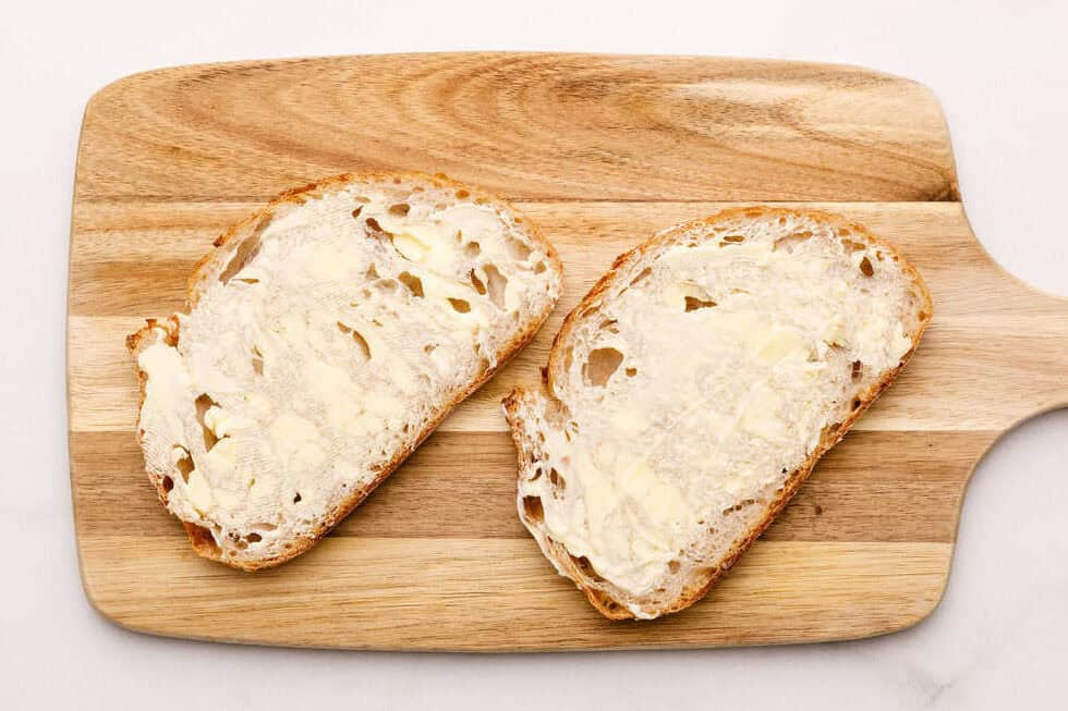 Two pieces of bread spread with butter. 