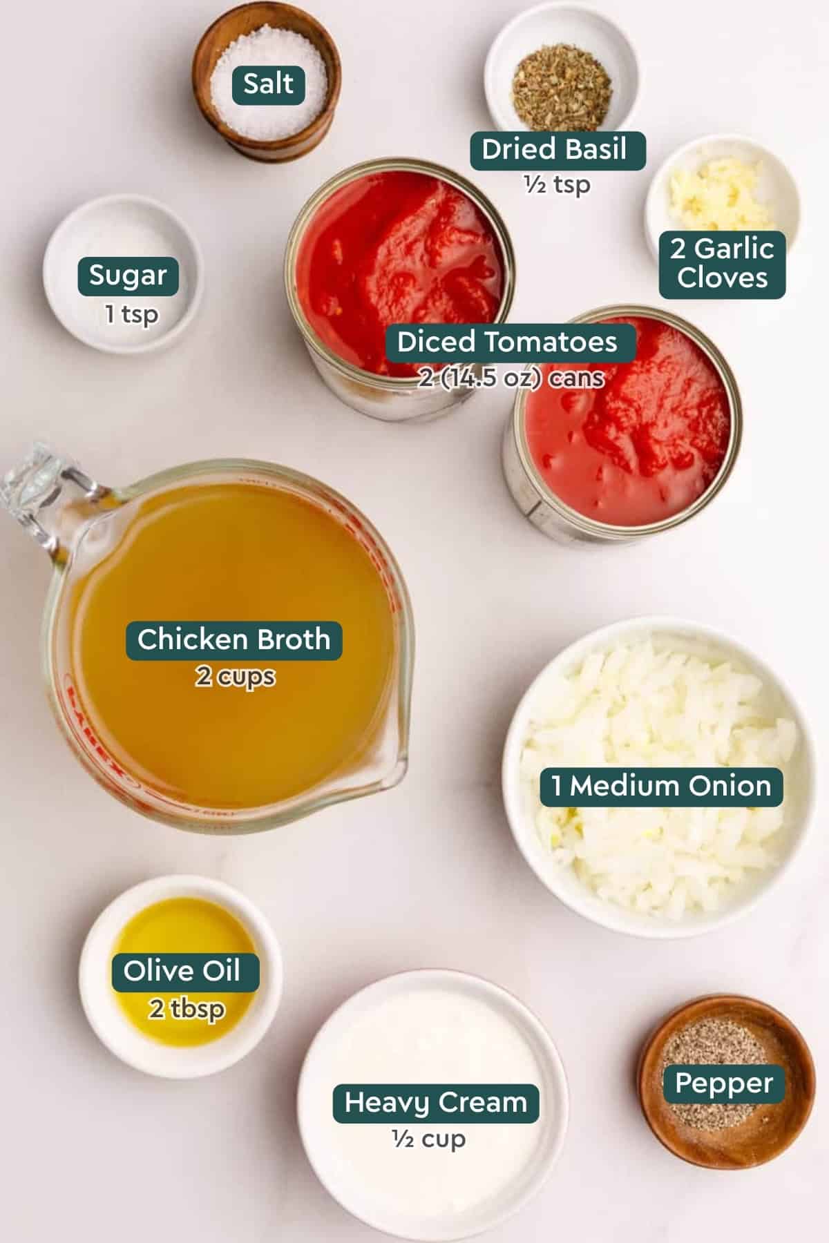 Ingredients for the best tomato soup, including canned tomatoes, salt, basil garlic, sugar, broth, onion, oil, cream, and pepper.