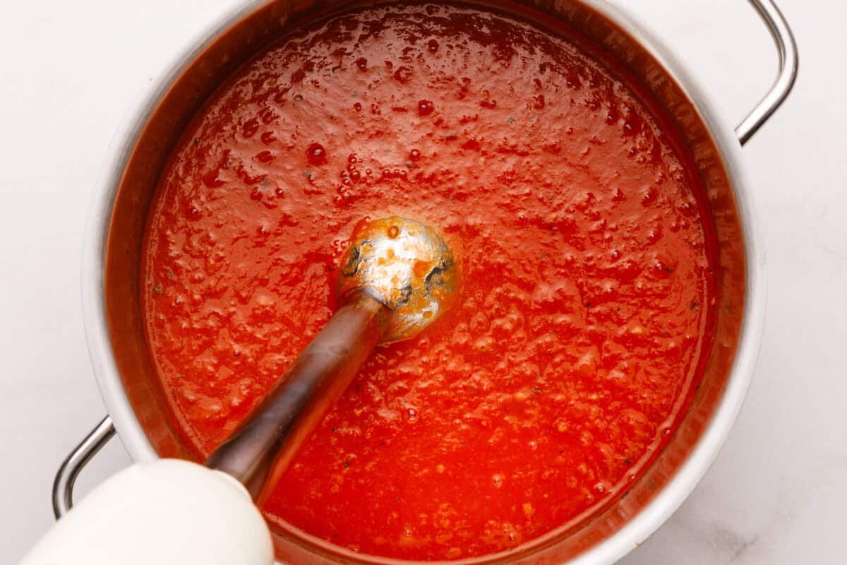 Immersion blender in a pot of tomato soup.