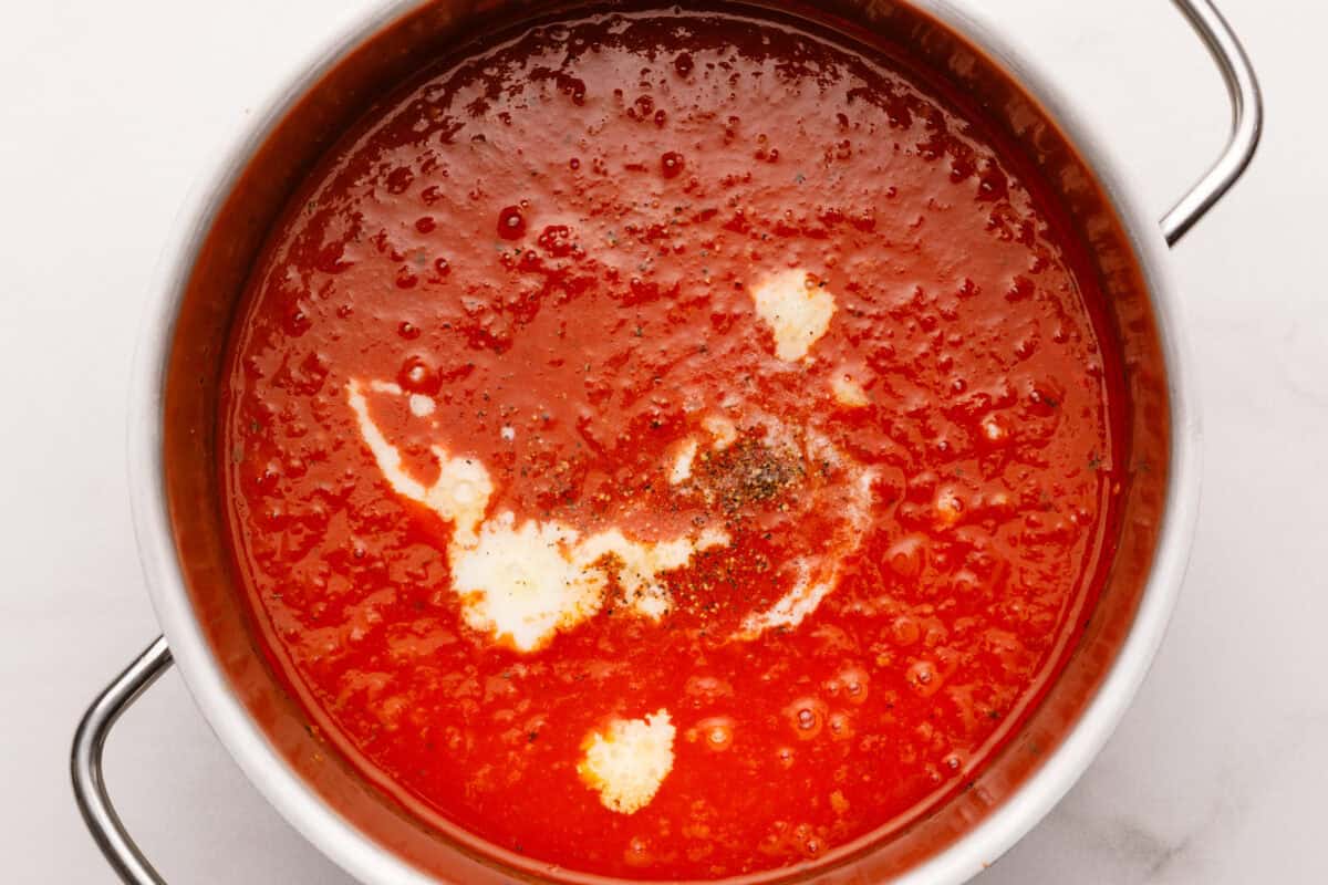 Heavy cream and pepper added to pot of tomato soup.