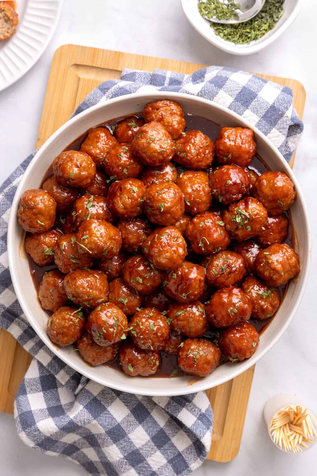 grape jelly meatballs in a white bowl with sauce. 