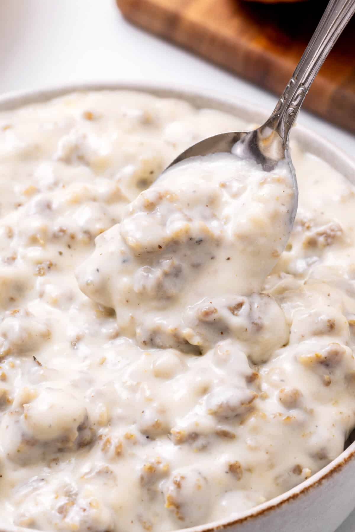 Buscuits with sausage gravy sausage gravy with a spoon.