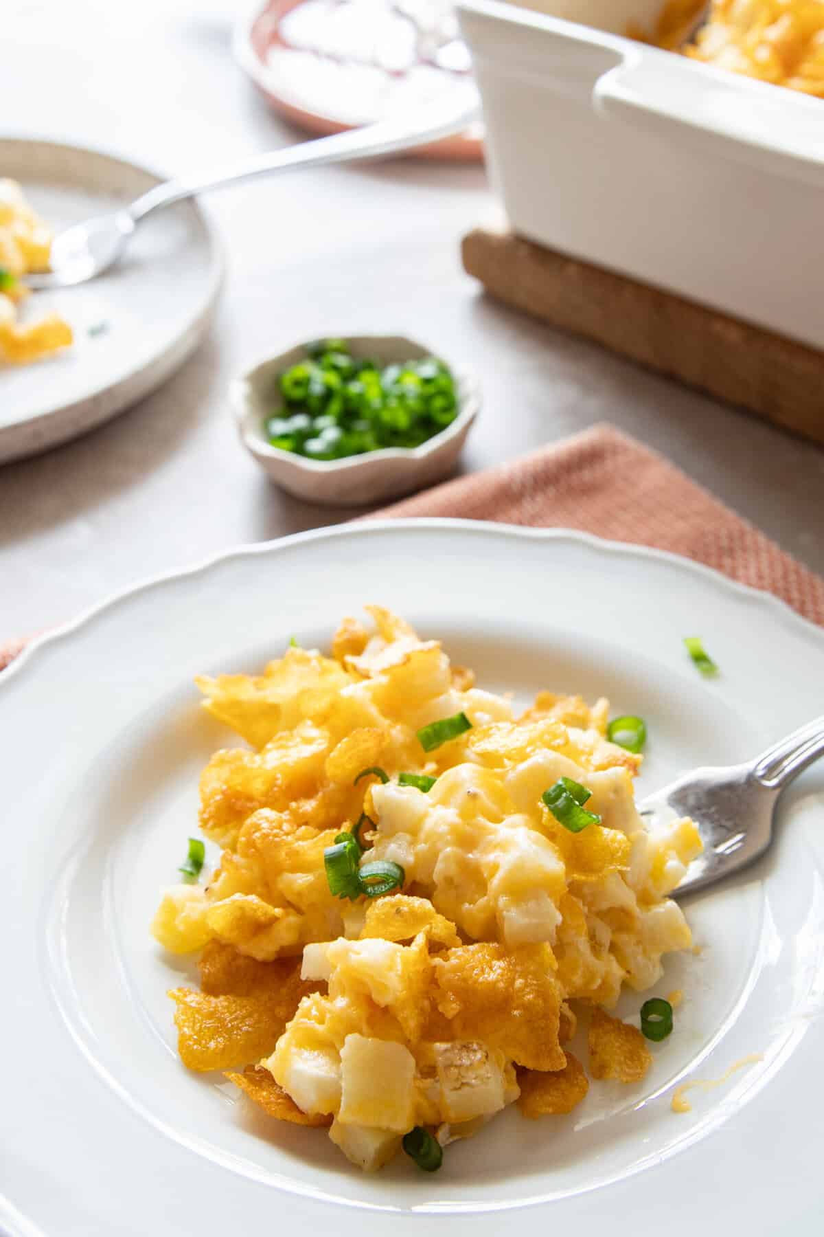 Easy Cheesy Potato Casserole Recipe Serving of cheesy potatoes on plate with fork