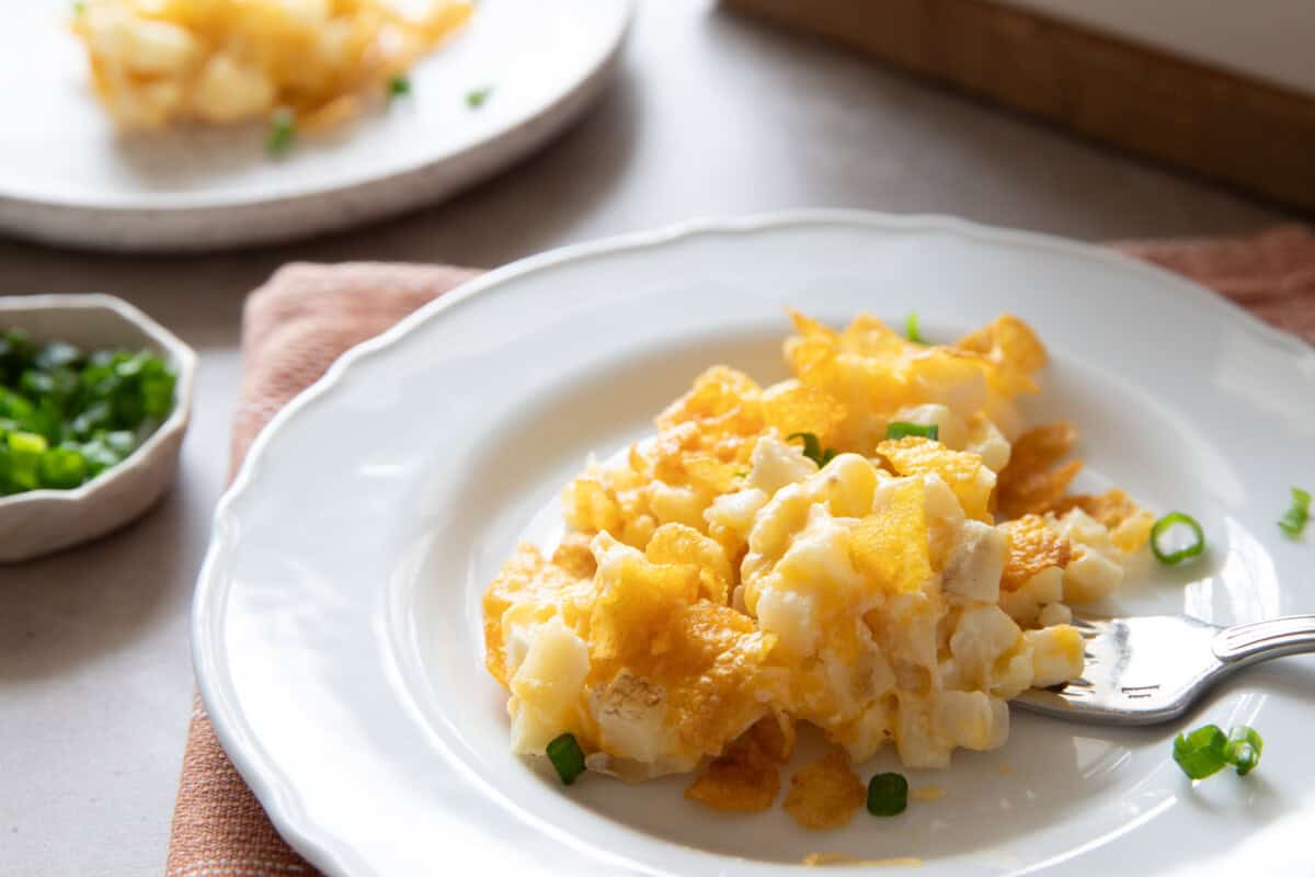 Serving of cheesy potatoes on plate with fork