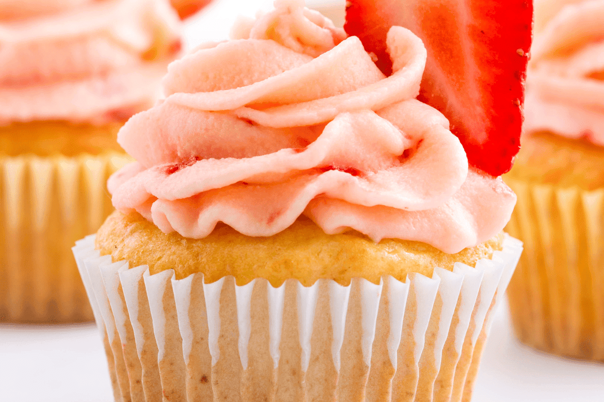 Strawberry lemon cupcakes with strawberry frosting and a halved strawberry.