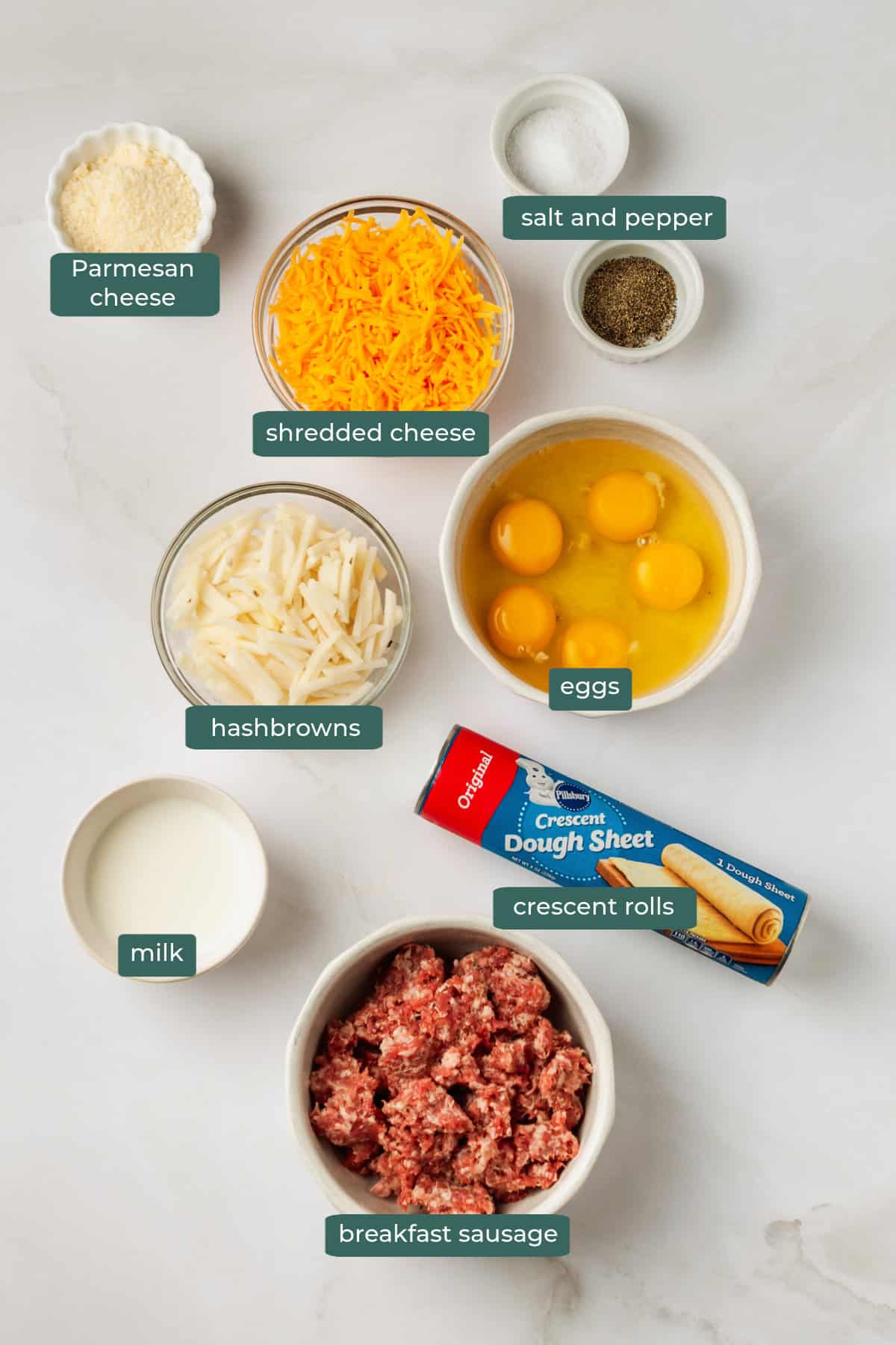 All of the ingredients for breakfast pizza made with crescent rolls in bowls on a white countertop.